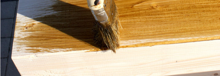 Pinsel trägt Lasur auf Holz auf